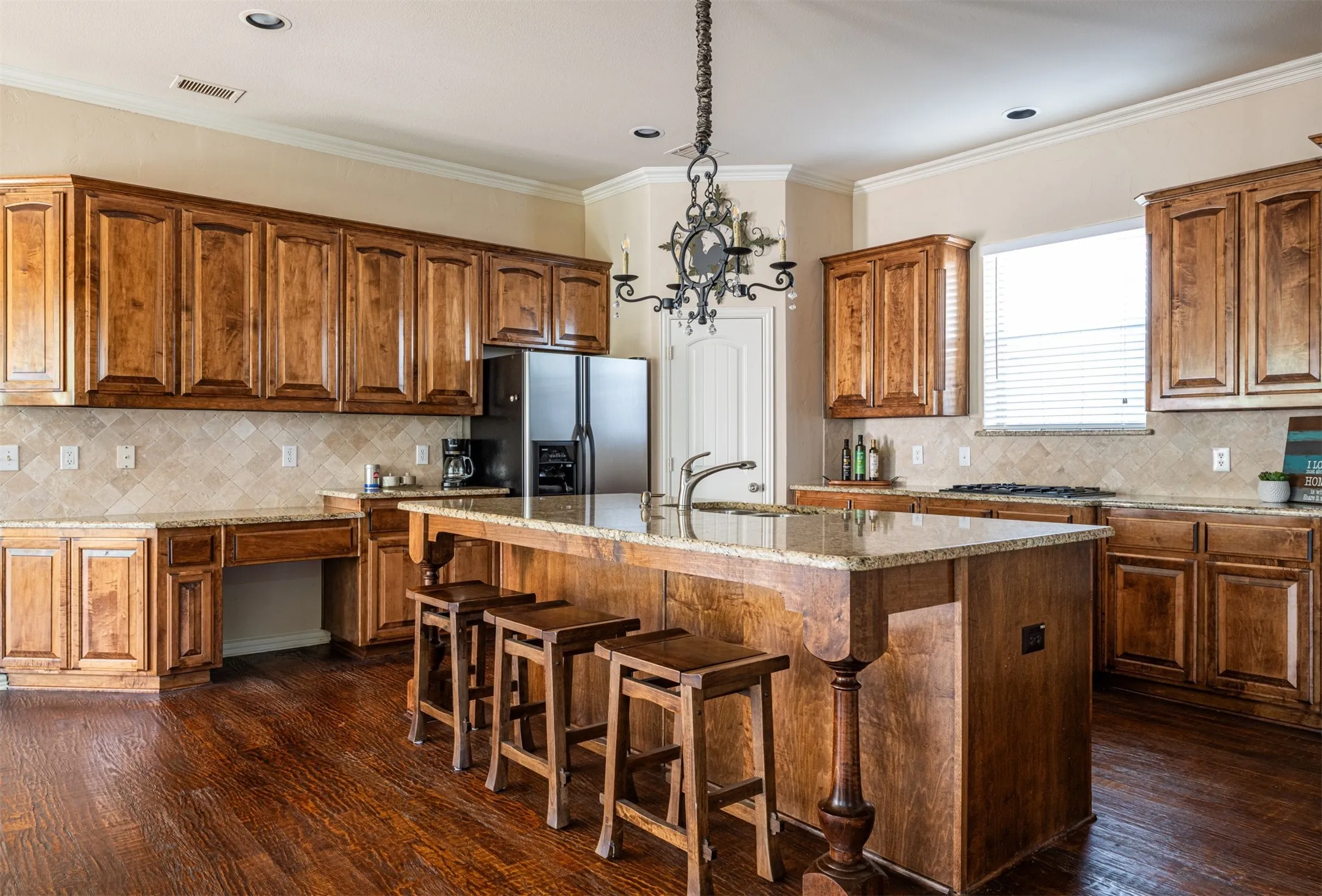 Kitchen with granite countertops, appliances and a custom built-in desk space and island dining