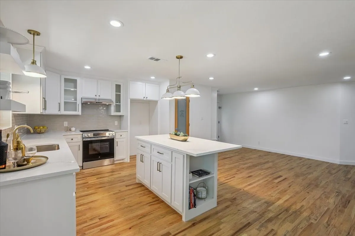 Kitchen featuring open shelves, decorative backsplash, glass insert cabinets, stainless steel electric stove, and white cabinetry