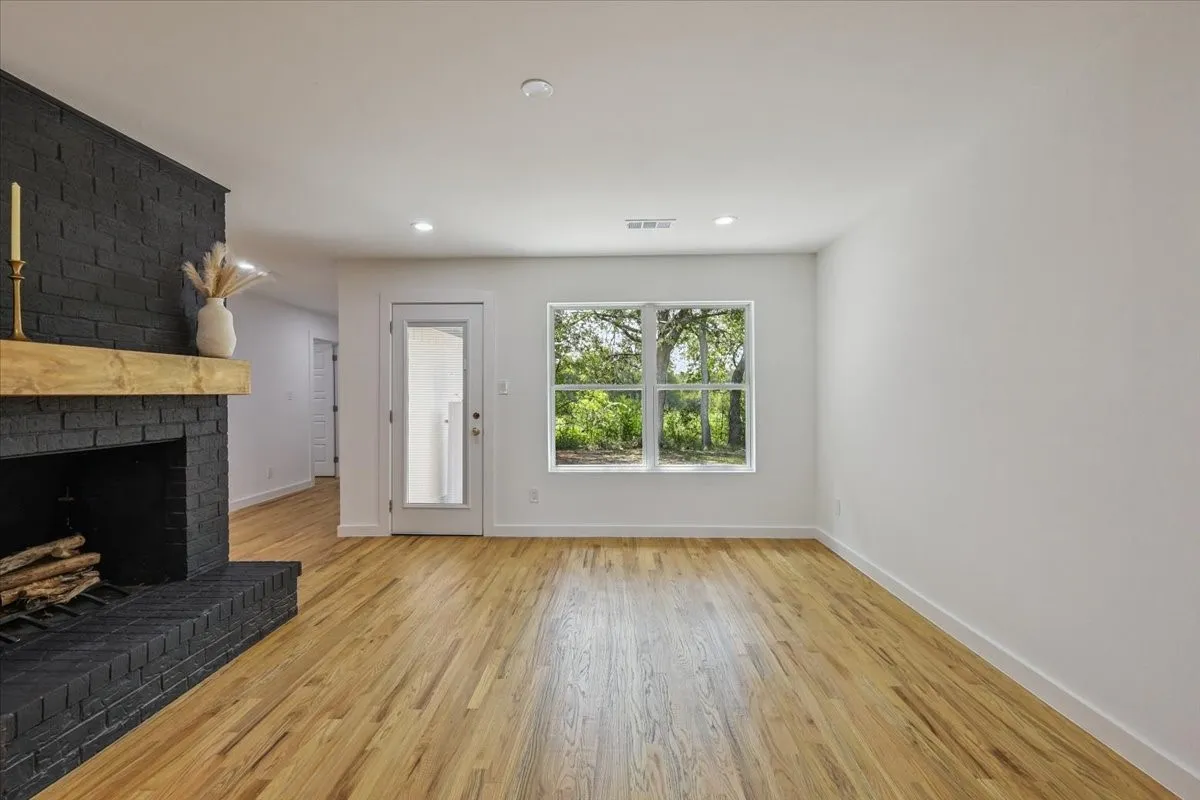 Unfurnished living room with light wood-type flooring, a brick fireplace, and recessed lighting