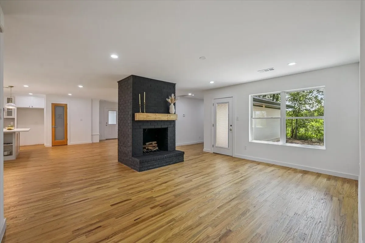Unfurnished living room featuring light wood-style flooring, a brick fireplace, and recessed lighting