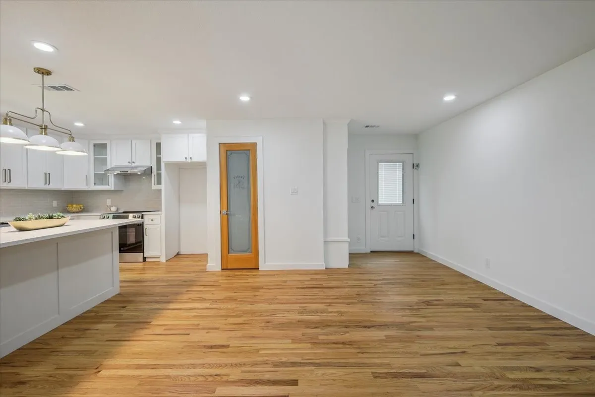 Kitchen featuring glass insert cabinets, white cabinetry, tasteful backsplash, light countertops, and light wood-style flooring