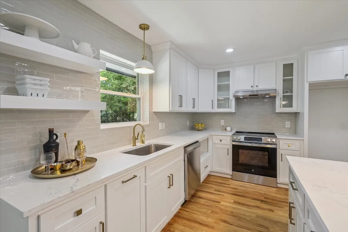 Kitchen featuring stainless steel appliances, tasteful backsplash, white cabinets, hanging light fixtures, and glass insert cabinets