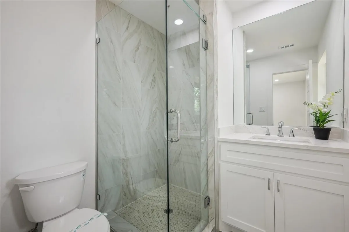 Bathroom featuring a marble finish shower and vanity
