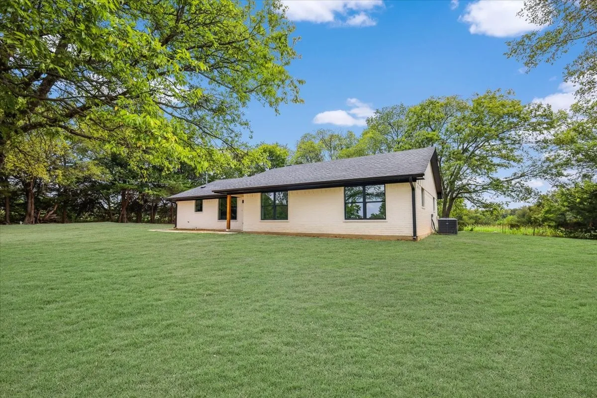 View of front of property with a front yard, brick siding, and roof with shingles
