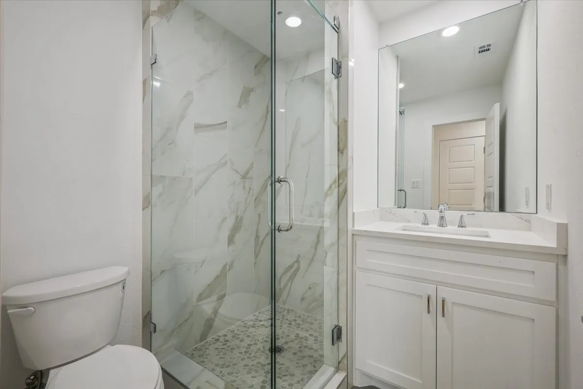 Full bathroom with a marble finish shower, vanity, and recessed lighting