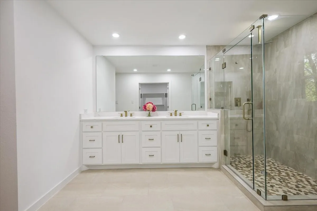 Full bath featuring double vanity, a shower stall, recessed lighting, and light tile patterned flooring