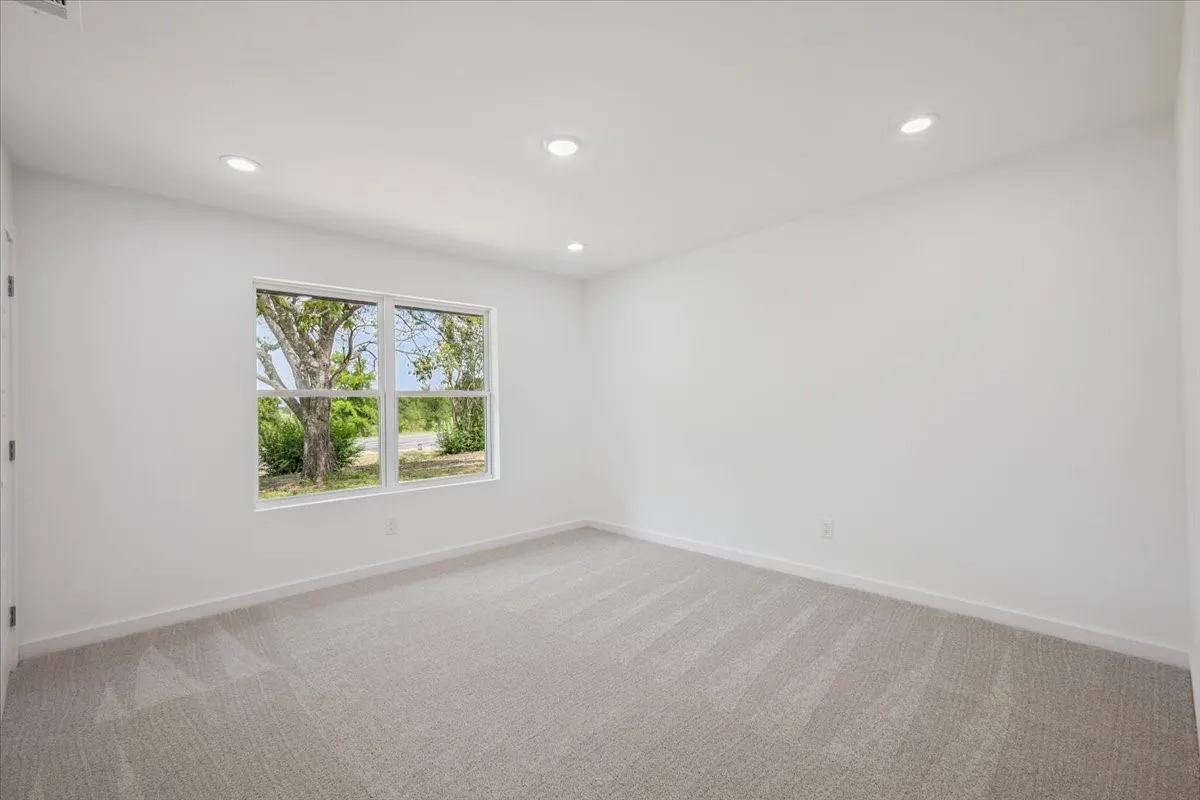 Empty room with recessed lighting and light colored carpet