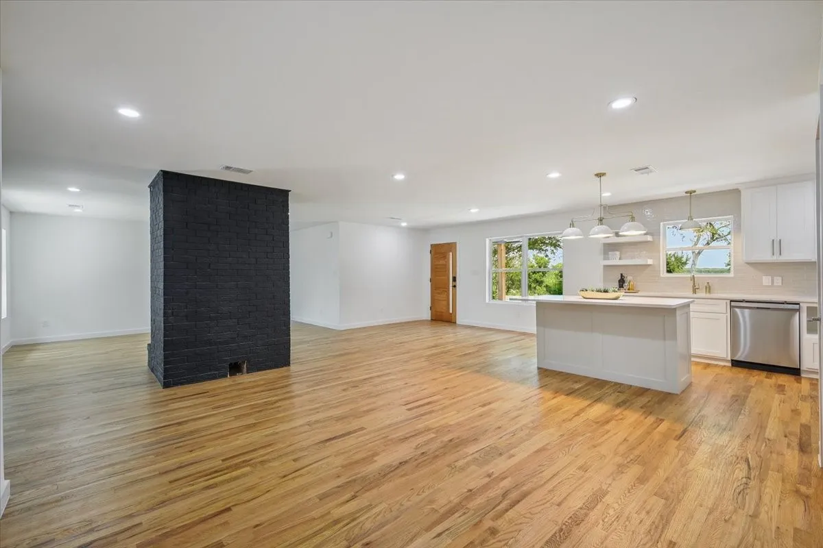 Kitchen with a center island, open shelves, open floor plan, white cabinets, and light wood finished floors