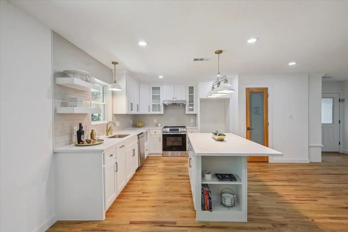 Kitchen featuring open shelves, white cabinetry, decorative backsplash, glass insert cabinets, and stainless steel appliances