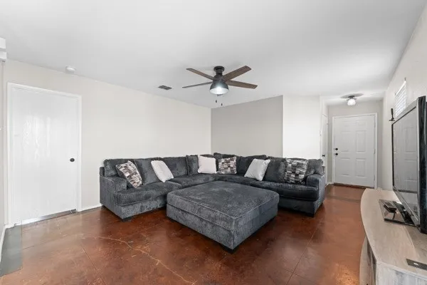 Living room featuring finished concrete floors and ceiling fan