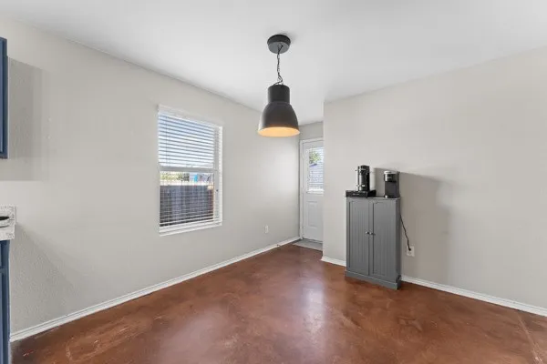 Unfurnished dining area with concrete flooring and baseboards