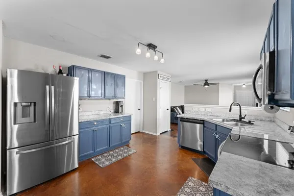 Kitchen featuring blue cabinets, stainless steel appliances, light countertops, and finished concrete floors