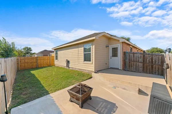 Rear view of property with a fire pit, a fenced backyard, and a patio