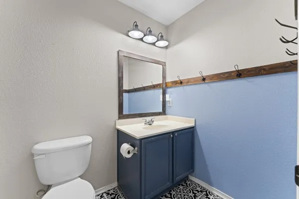 Half bathroom featuring a textured wall and vanity
