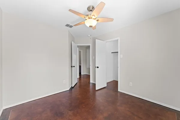 Unfurnished bedroom featuring finished concrete floors, ceiling fan, and a spacious closet
