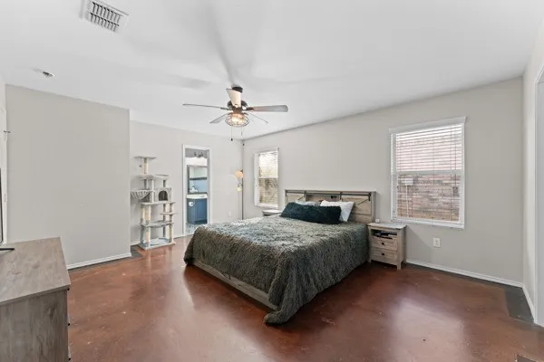 Bedroom with multiple windows, concrete floors, and ceiling fan