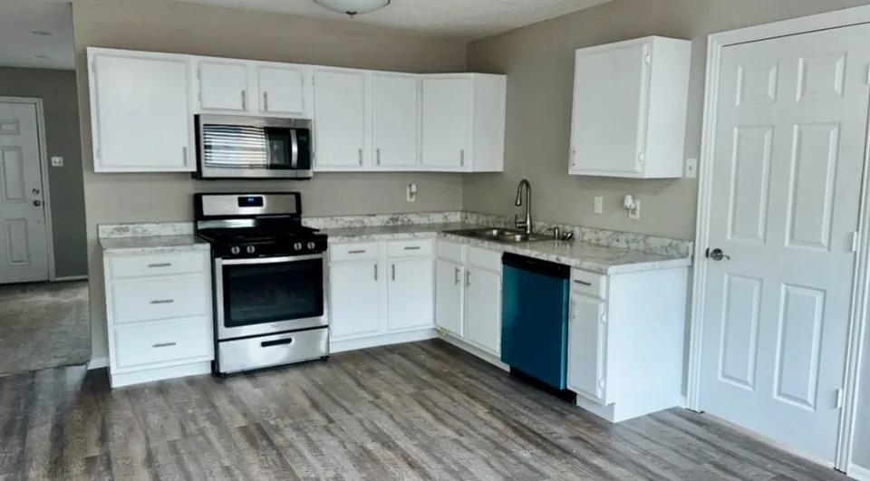 Kitchen featuring white cabinets, sink, stainless steel appliances