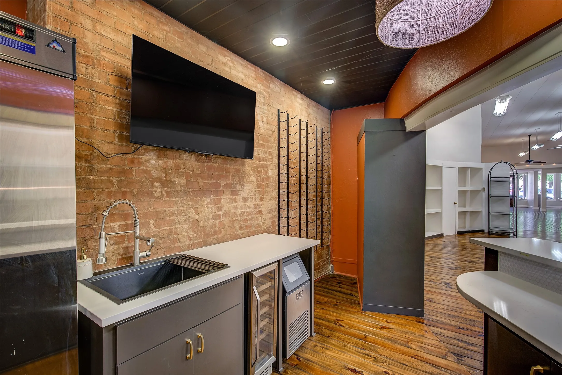 Service area behind the bar. Sink, wine cooler, ice machine and refrigerator, with wine racks and TV.