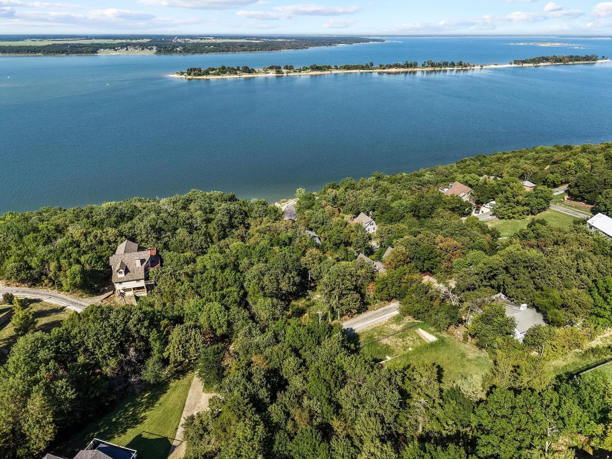 Aerial overview of property's location featuring a nearby body of water and a heavily wooded area
