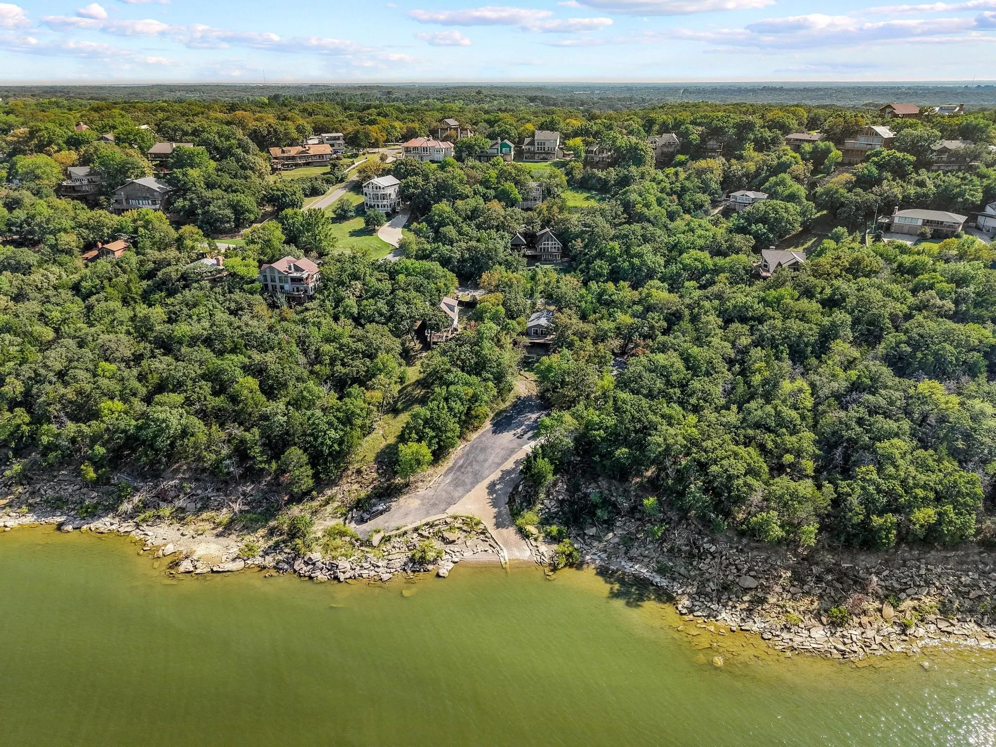 Aerial view of property and surrounding area with a large body of water and a heavily wooded area