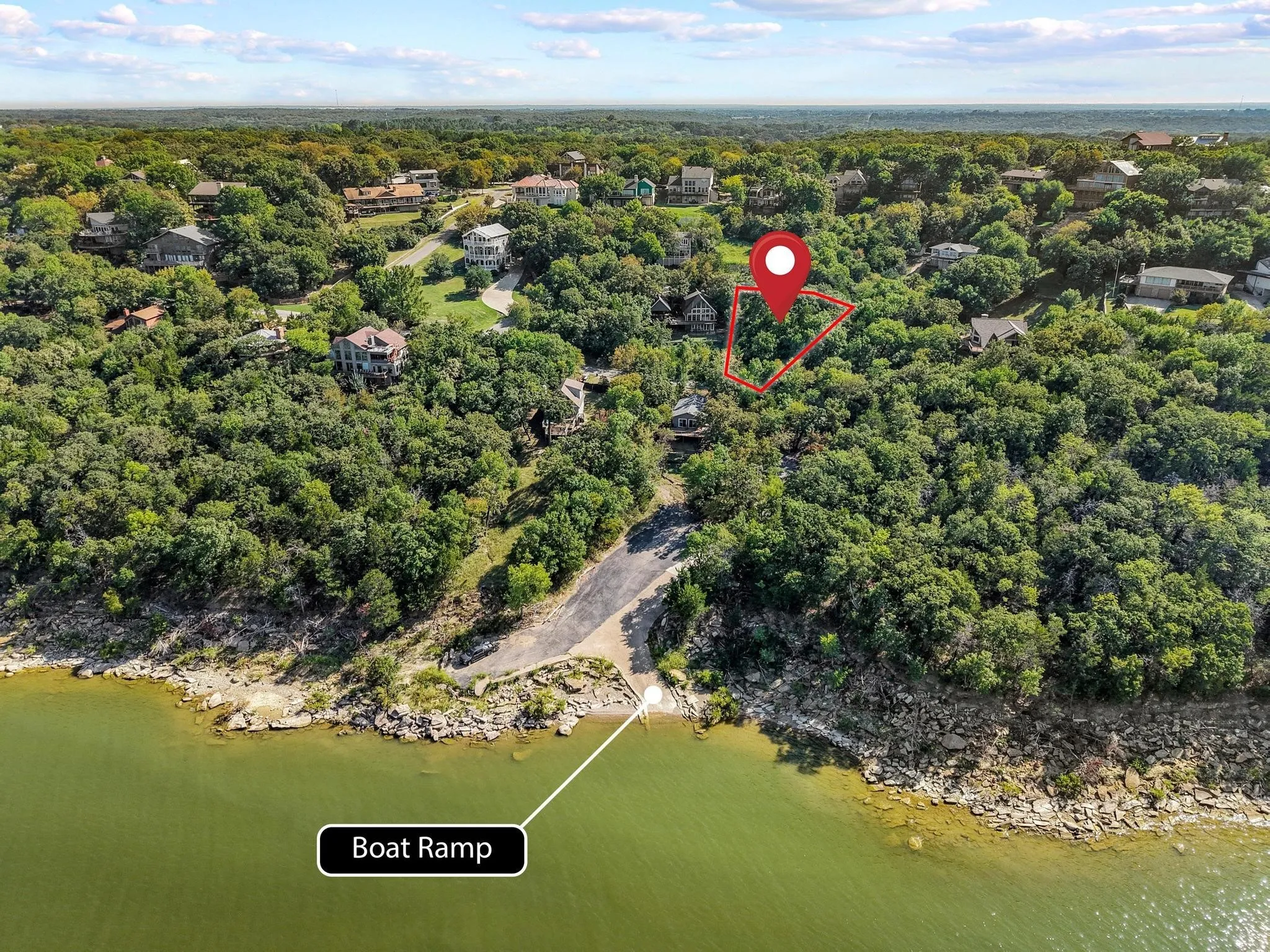 Aerial view of property and surrounding area featuring a nearby body of water and a forest