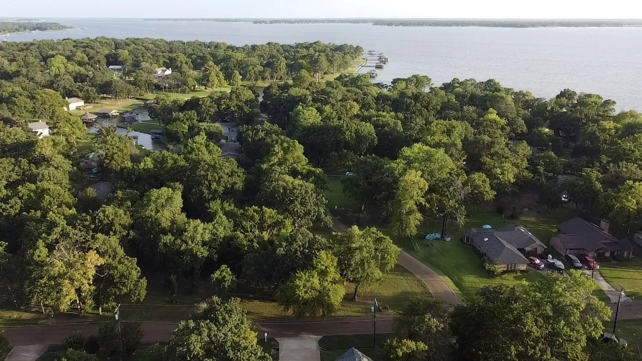 Aerial view of property and surrounding area featuring a nearby body of water and nearby suburban area