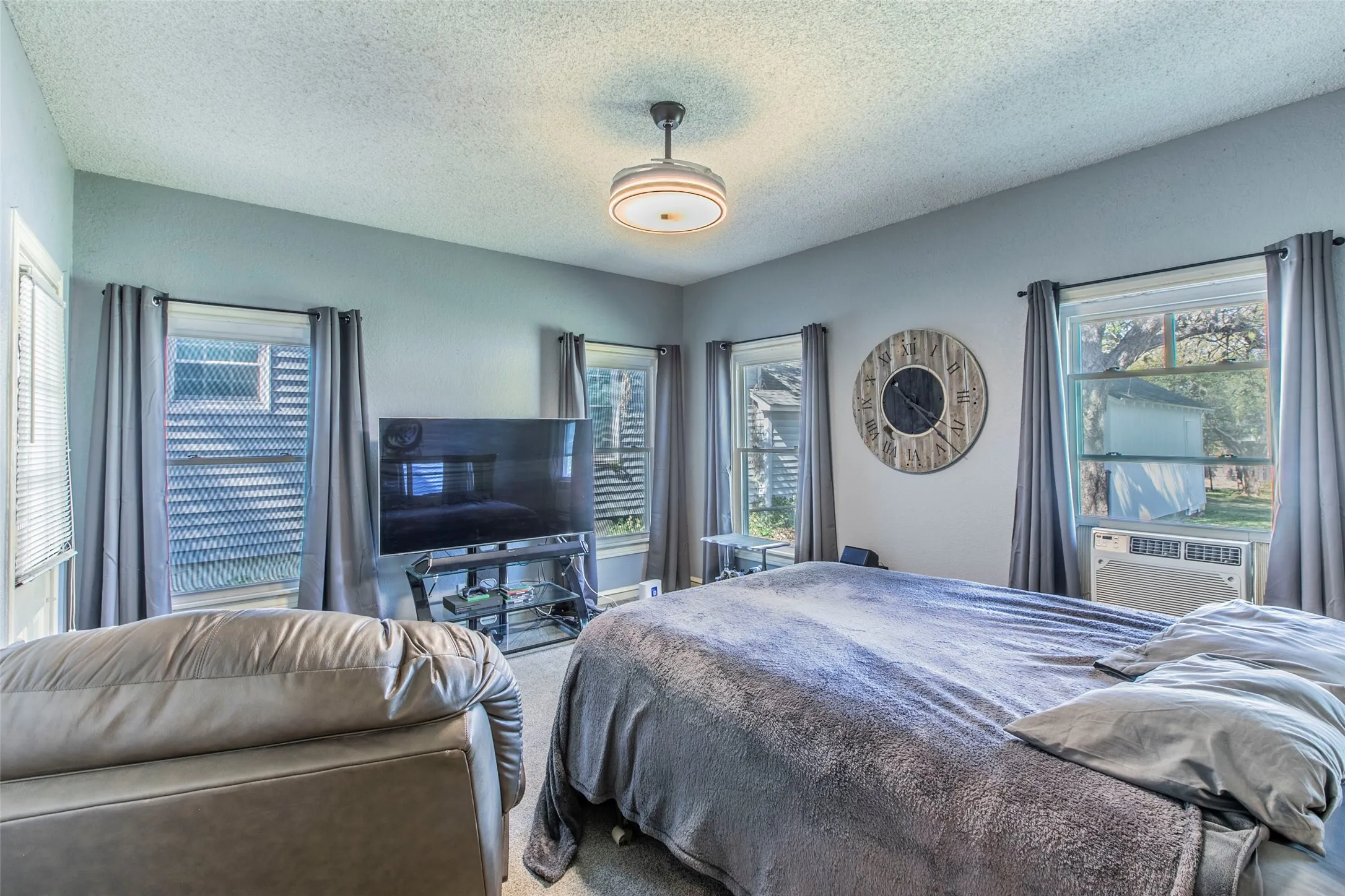 Carpeted bedroom with a textured ceiling and cooling unit