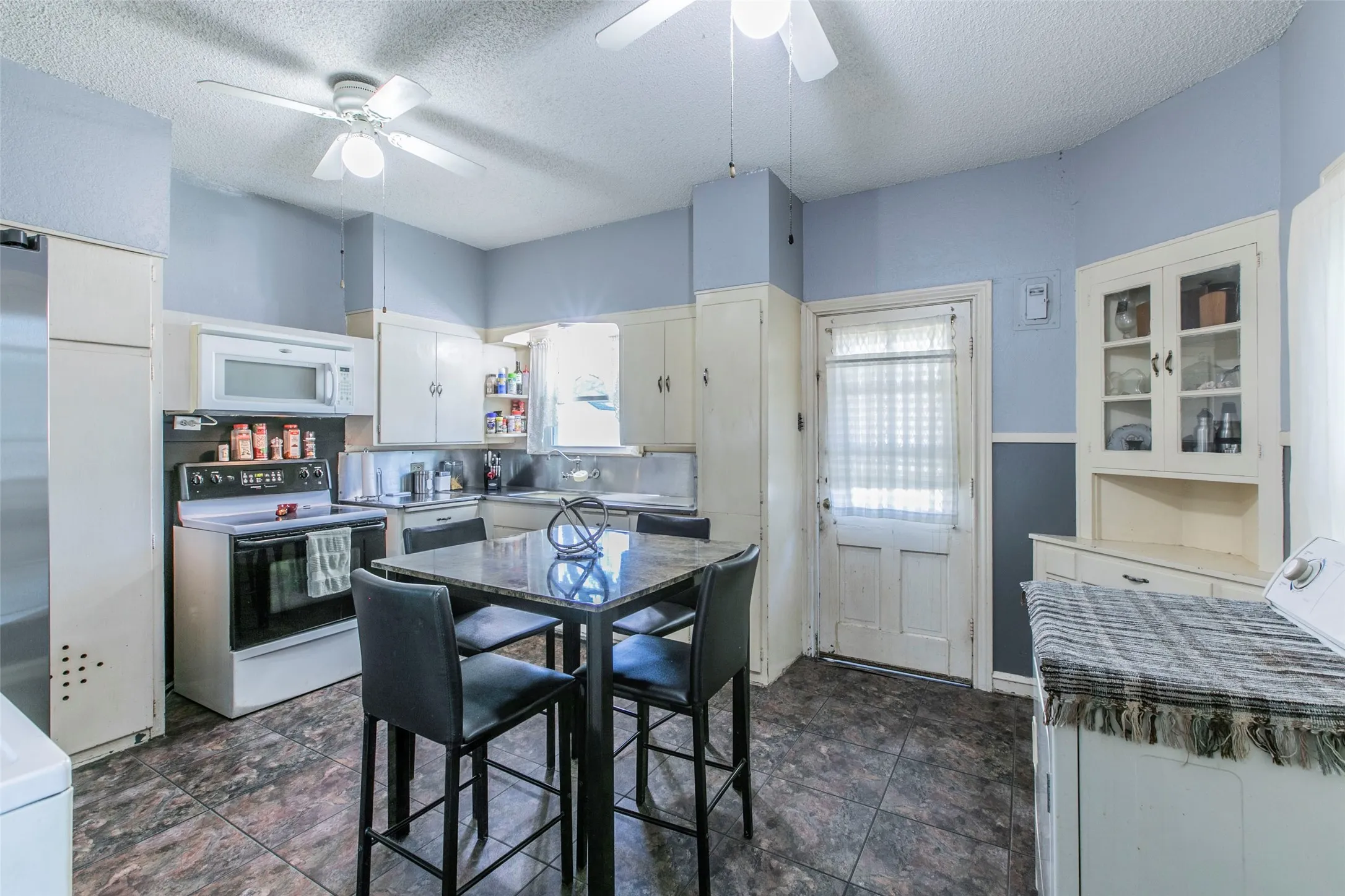 Kitchen featuring white appliances, washer / clothes dryer, a textured ceiling, white cabinetry, and a ceiling fan