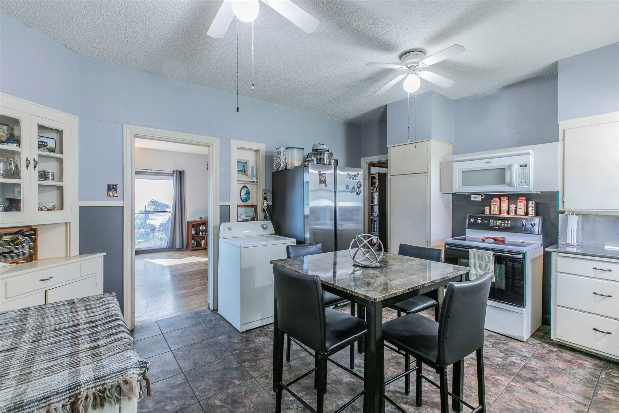 Kitchen with electric range oven, washer / clothes dryer, white cabinets, a textured ceiling, and white microwave