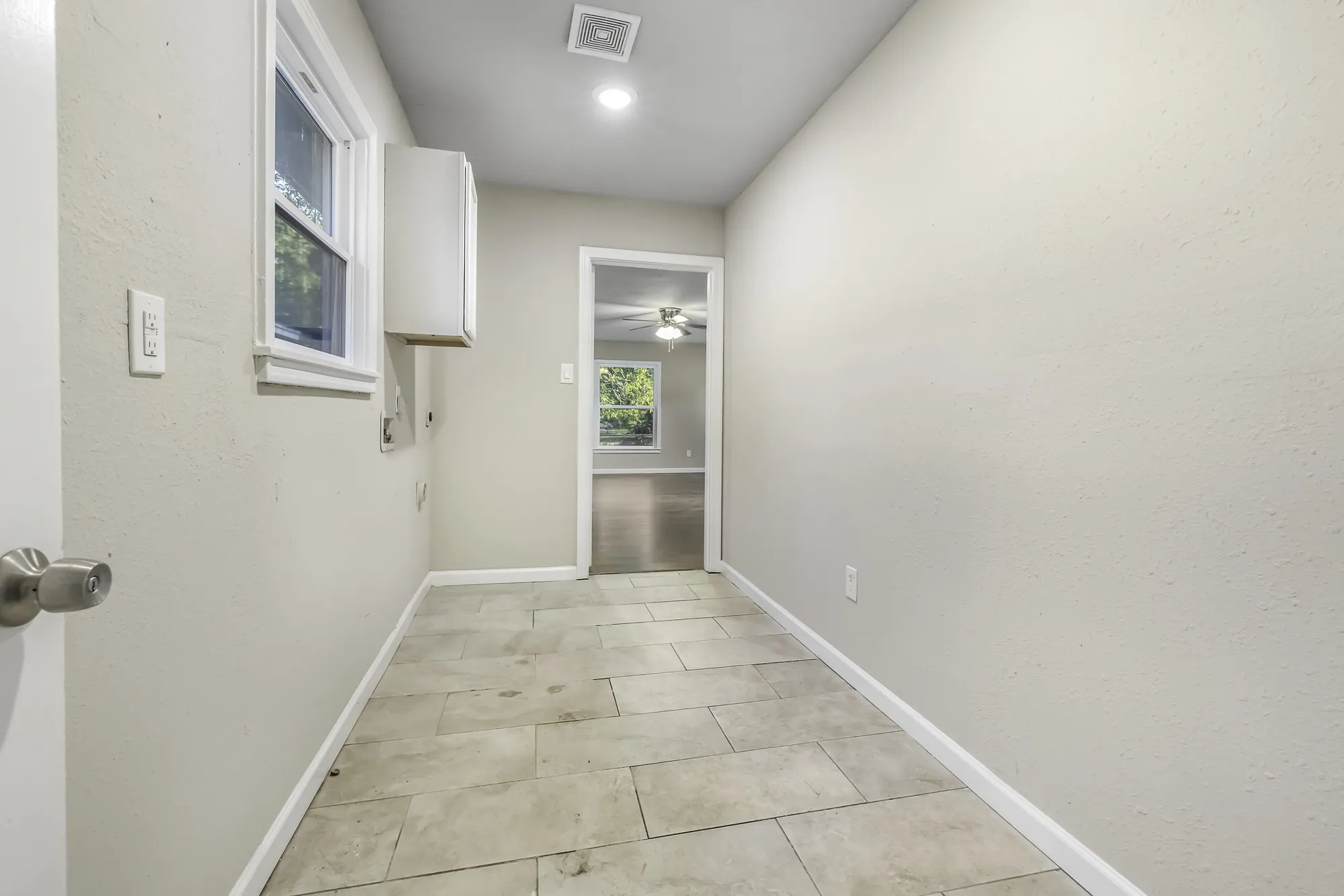 Corridor featuring light tile patterned floors and a textured wall