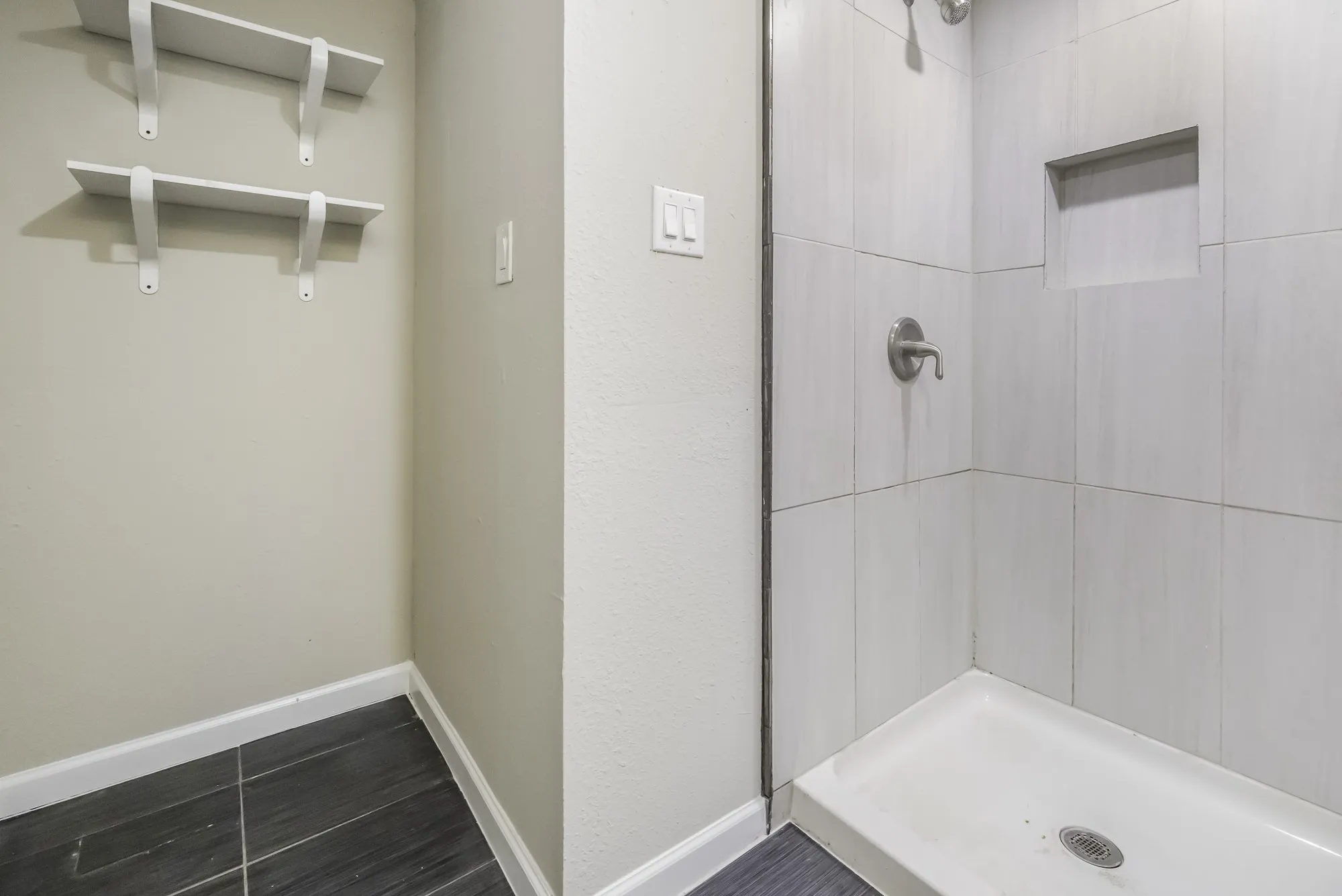 Bathroom with a shower stall and baseboards