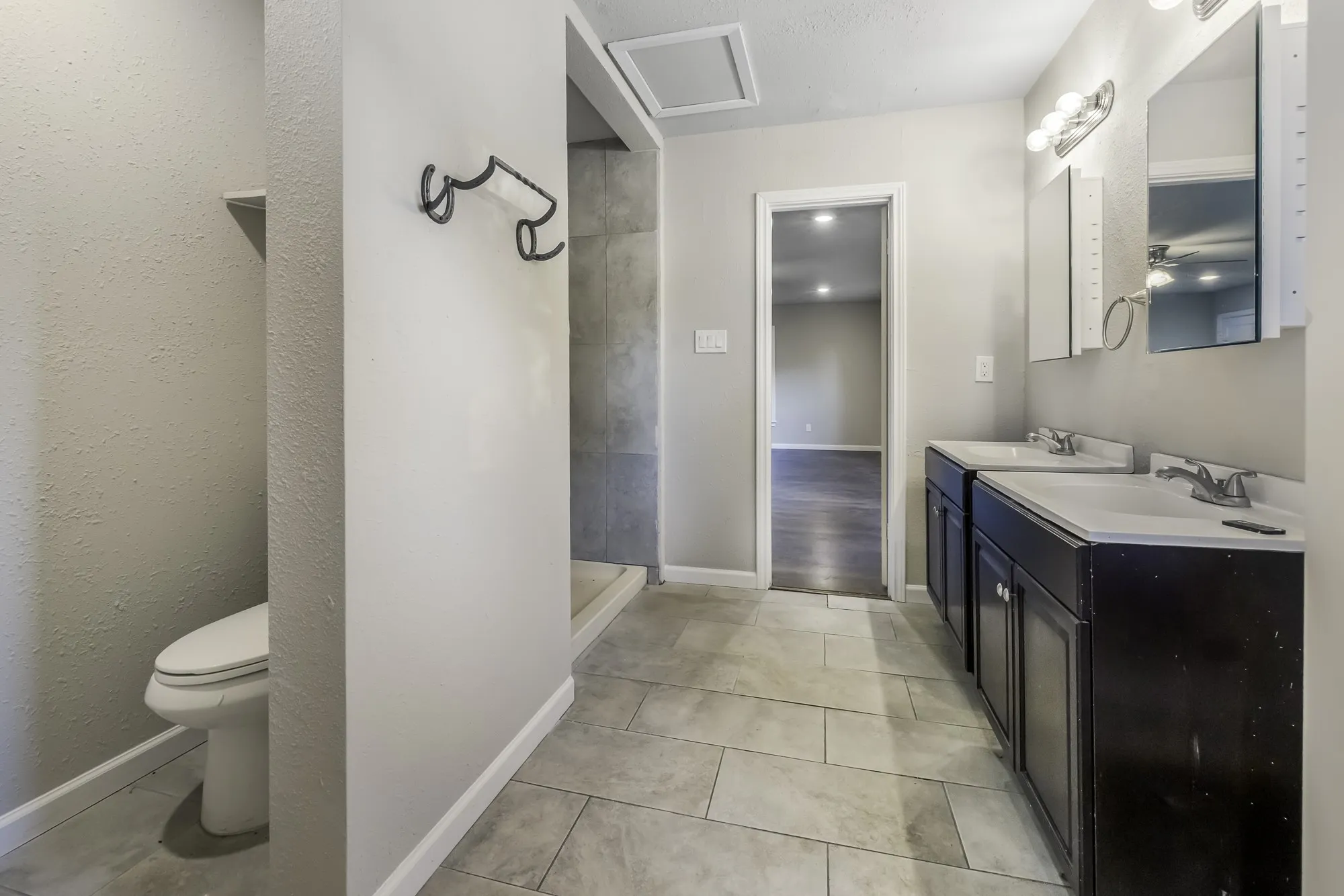 Full bath with double vanity, a stall shower, and light tile patterned floors