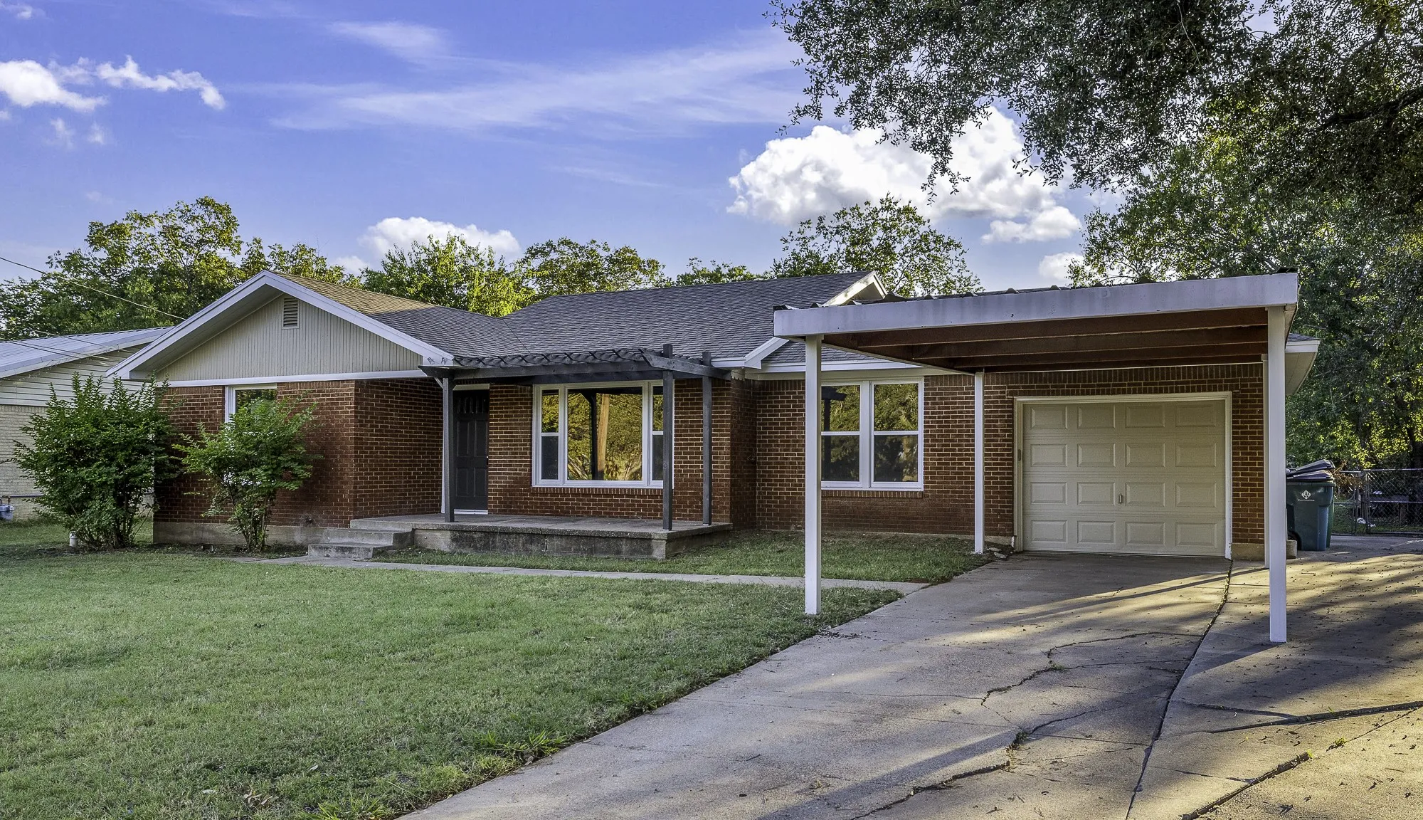 Ranch-style house with brick siding, driveway, a front lawn, roof with shingles, and an attached garage