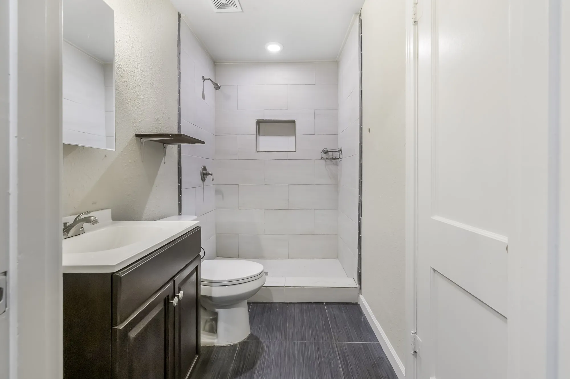 Full bath featuring vanity, a shower stall, and a textured wall