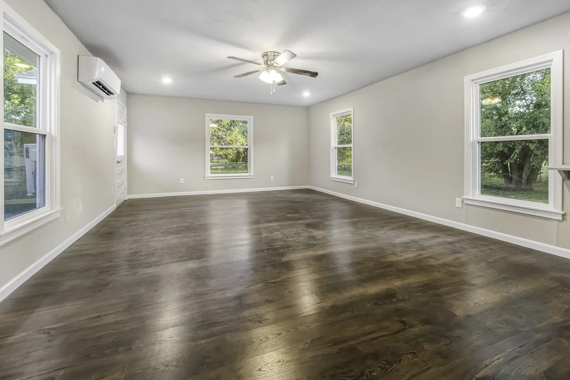 Empty room with dark wood-style flooring, recessed lighting, ceiling fan, and a wall mounted air conditioner