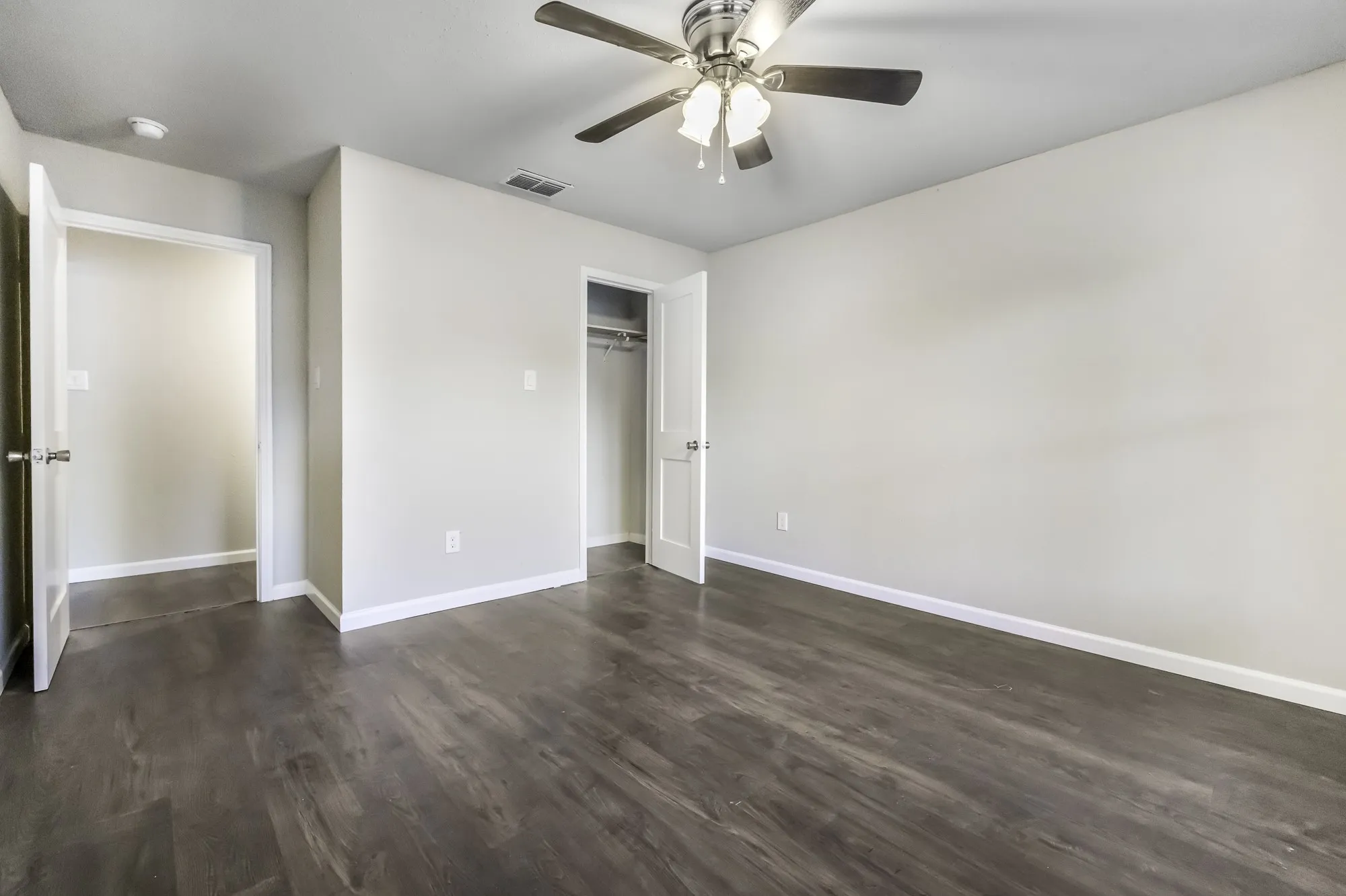 Unfurnished bedroom featuring dark wood-type flooring, a ceiling fan, and a closet