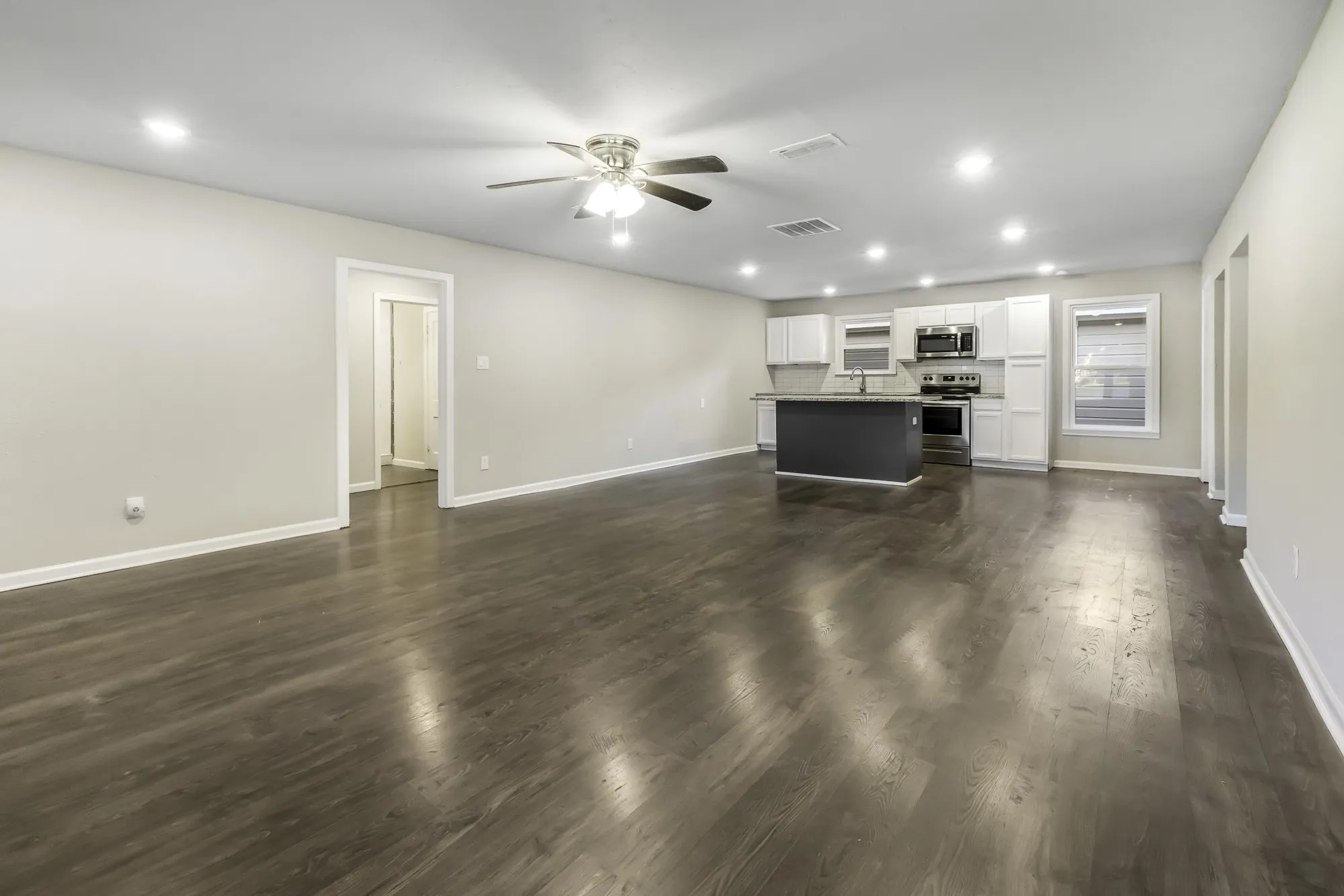 Unfurnished living room featuring recessed lighting, dark wood-style flooring, and a ceiling fan