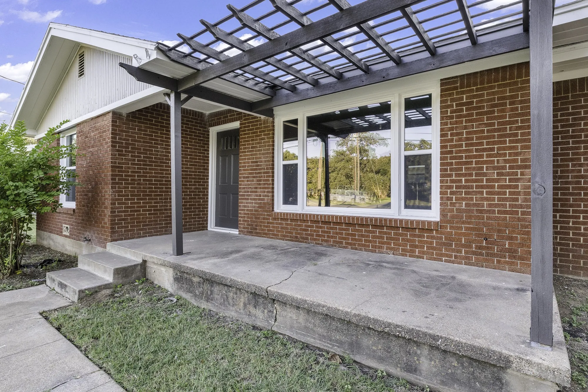 View of exterior entry featuring a pergola and brick siding