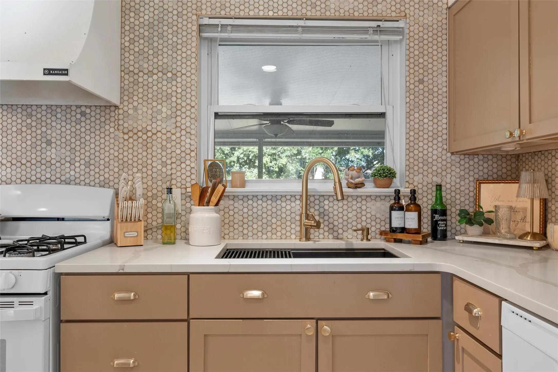 Kitchen with white appliances, under cabinet range hood, and light stone counters