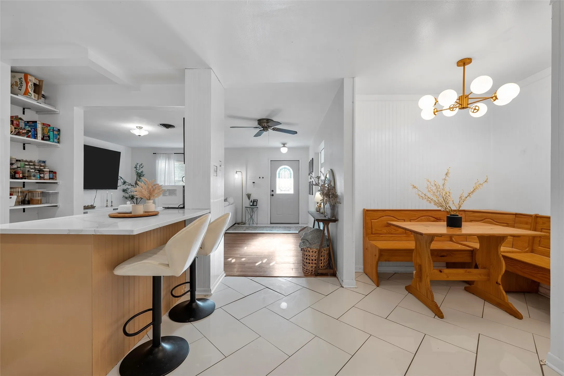 Kitchen with a breakfast bar, light tile patterned flooring, light stone countertops, hanging light fixtures, and a chandelier