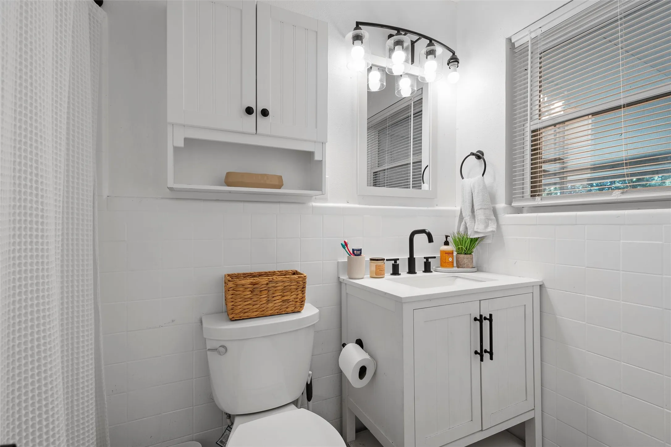 Bathroom featuring tile walls, wainscoting, vanity, and a shower with shower curtain