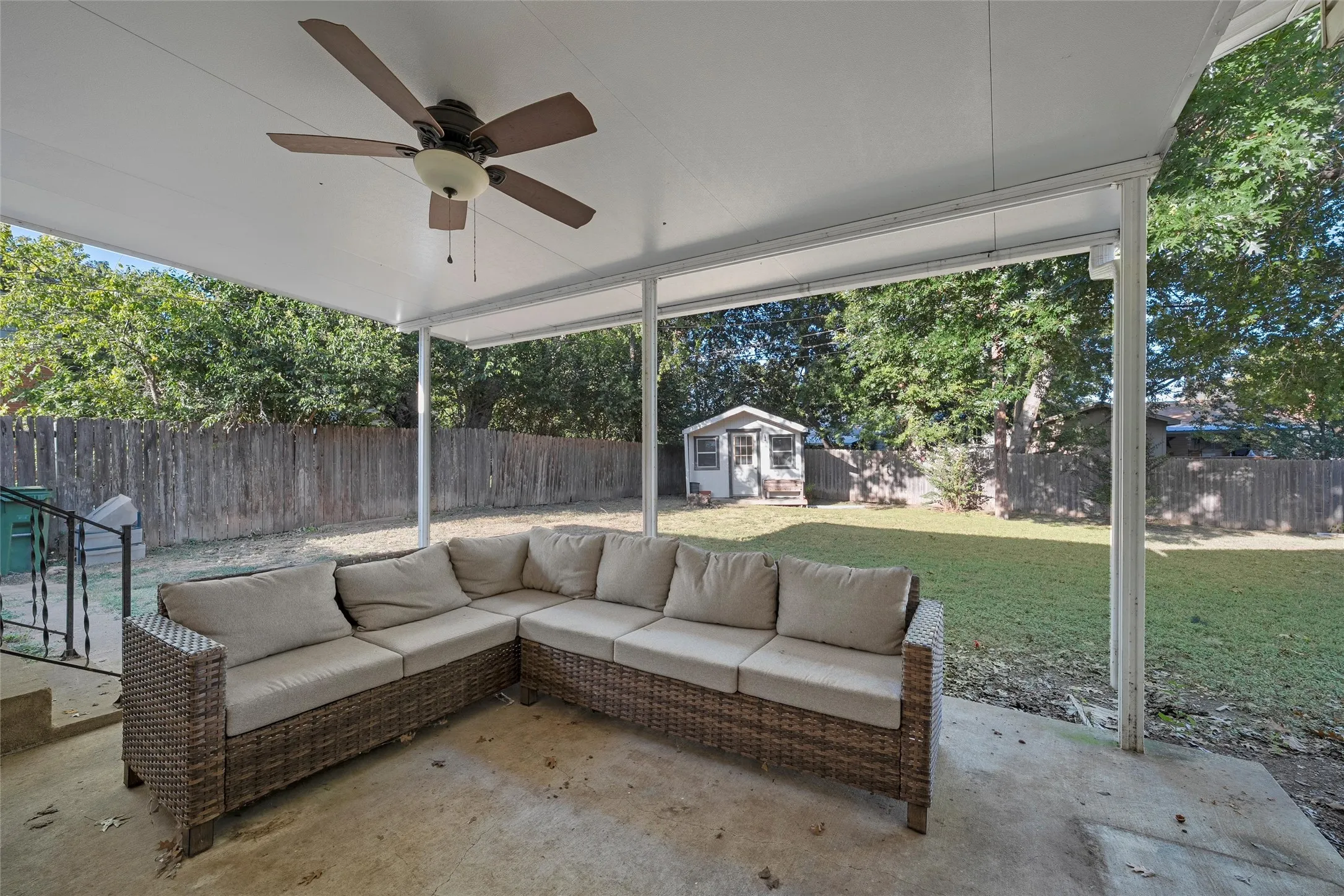 Fenced backyard featuring a patio area, an outdoor structure, outdoor lounge area, and a ceiling fan