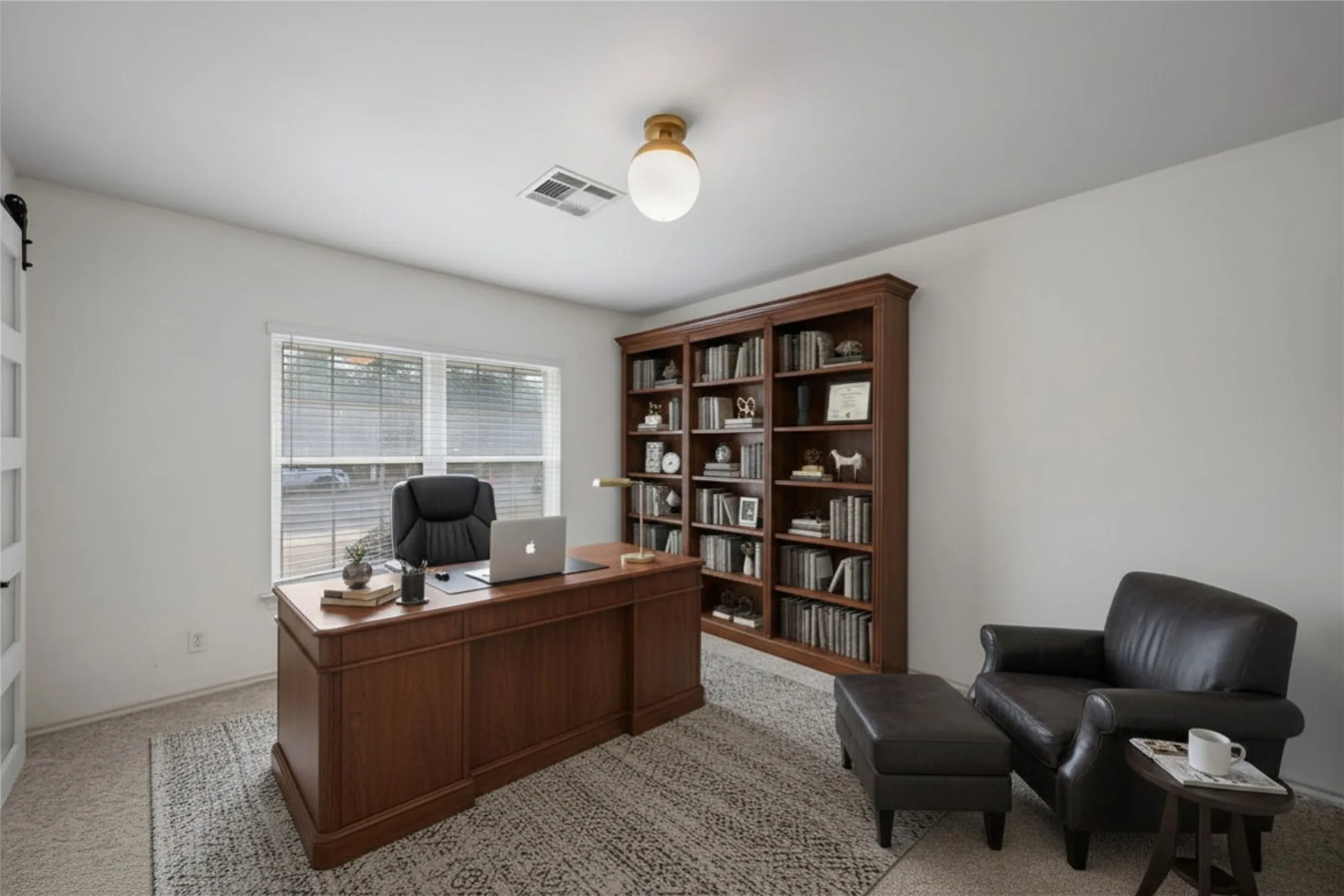 Dedicated room featuring a large window with blinds, carpeted flooring, and a ceiling-mounted light fixture