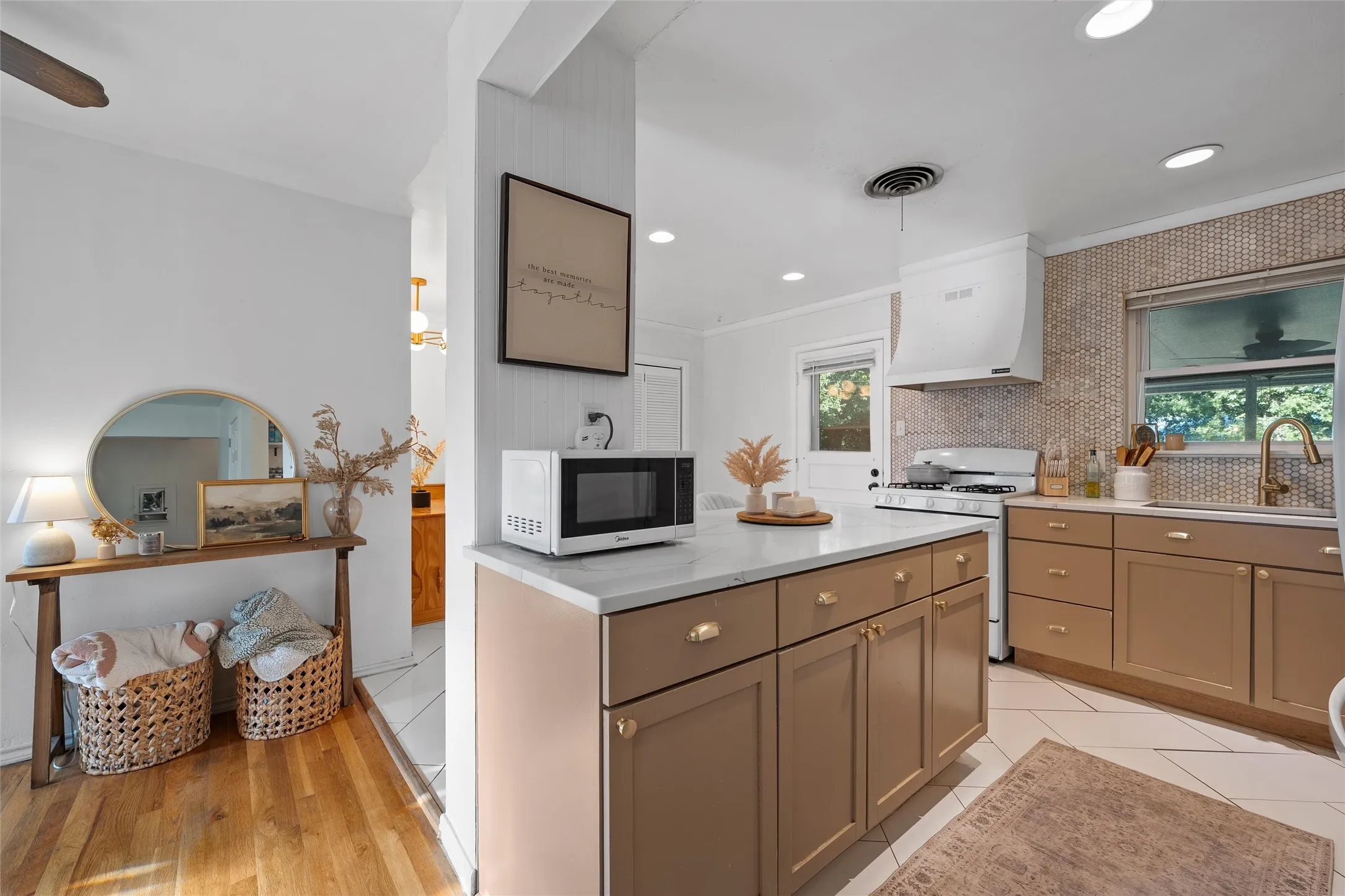 Kitchen featuring healthy amount of natural light, white appliances, wall chimney exhaust hood, light stone countertops, and recessed lighting