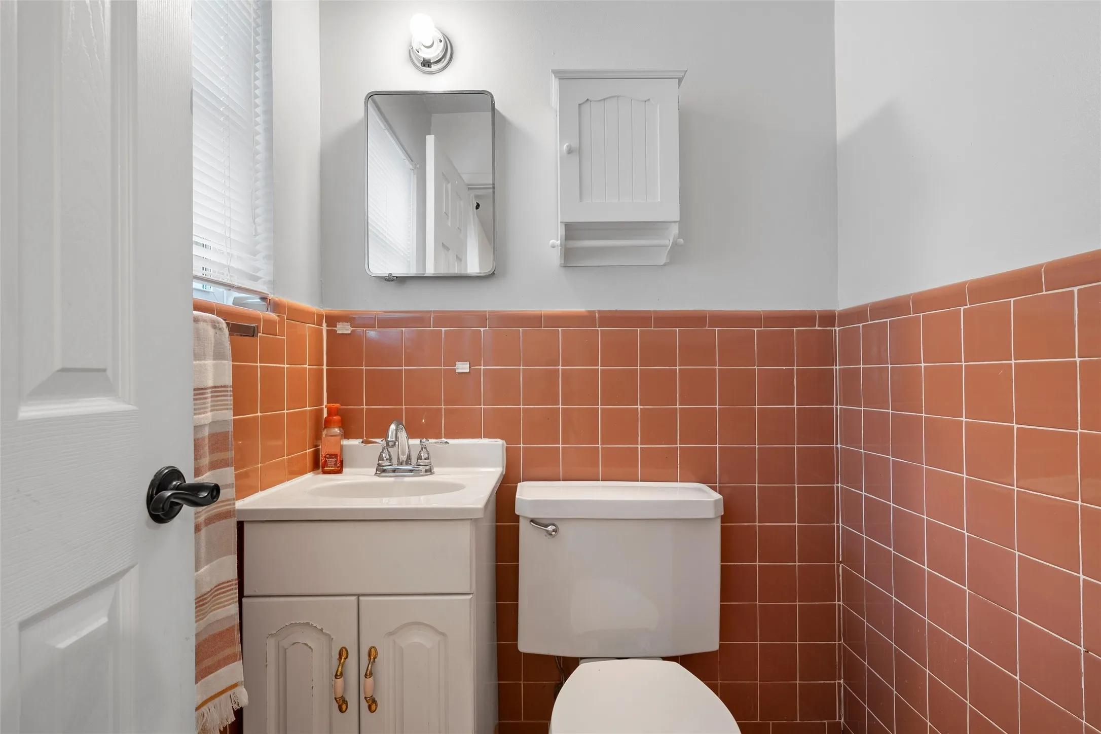 Bathroom featuring tile walls, vanity, and wainscoting