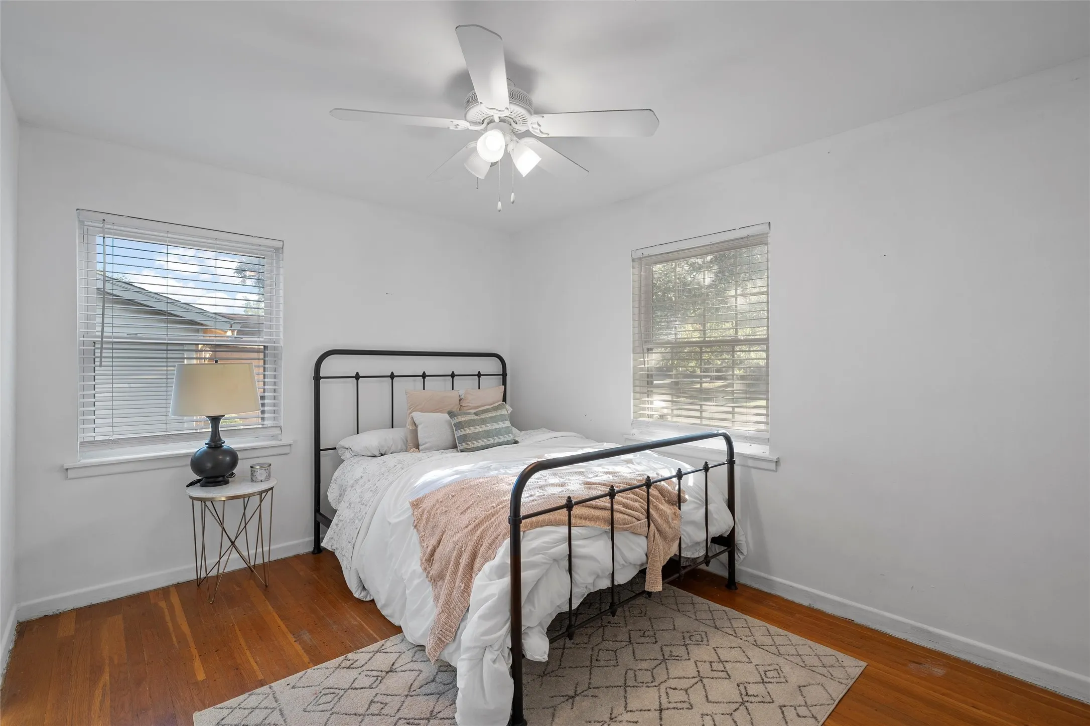 Bedroom featuring wood finished floors, a ceiling fan, and multiple windows
