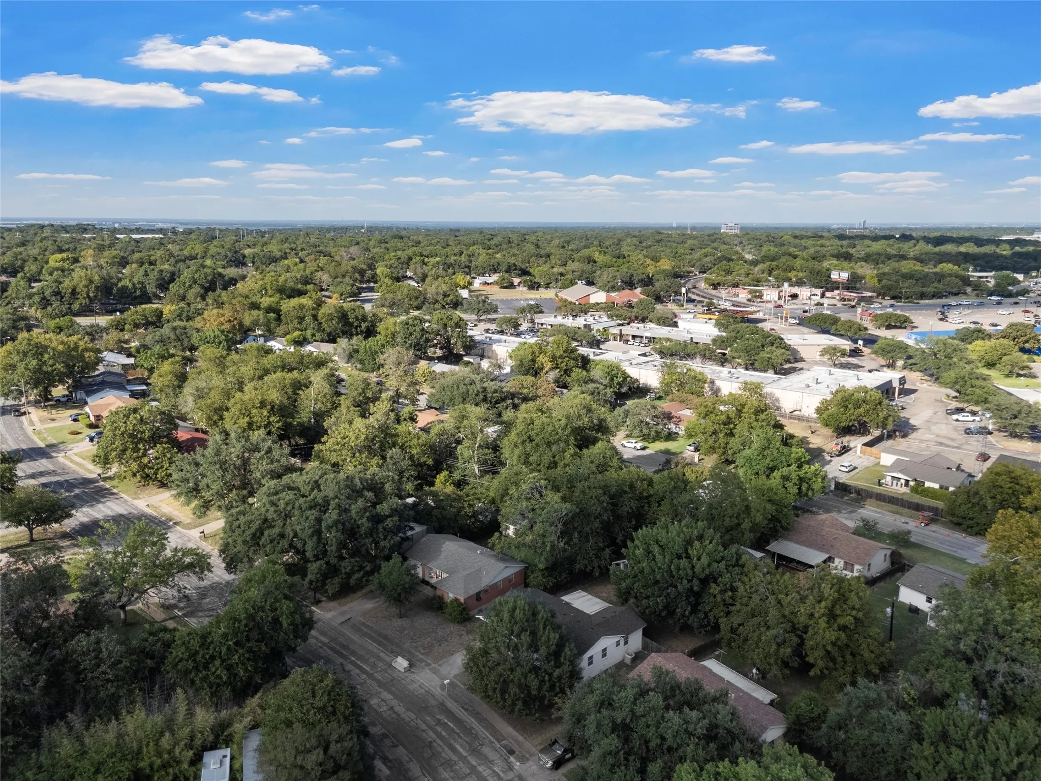 Aerial overview of property's location with nearby suburban area and a heavily wooded area