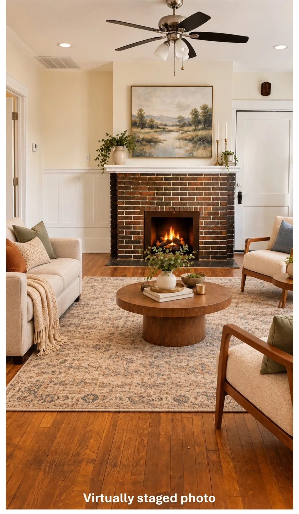 Virtually staged view of living room ffeaturing wood-type flooring, a fireplace, a decorative wall, a ceiling fan, and a wainscoted wall