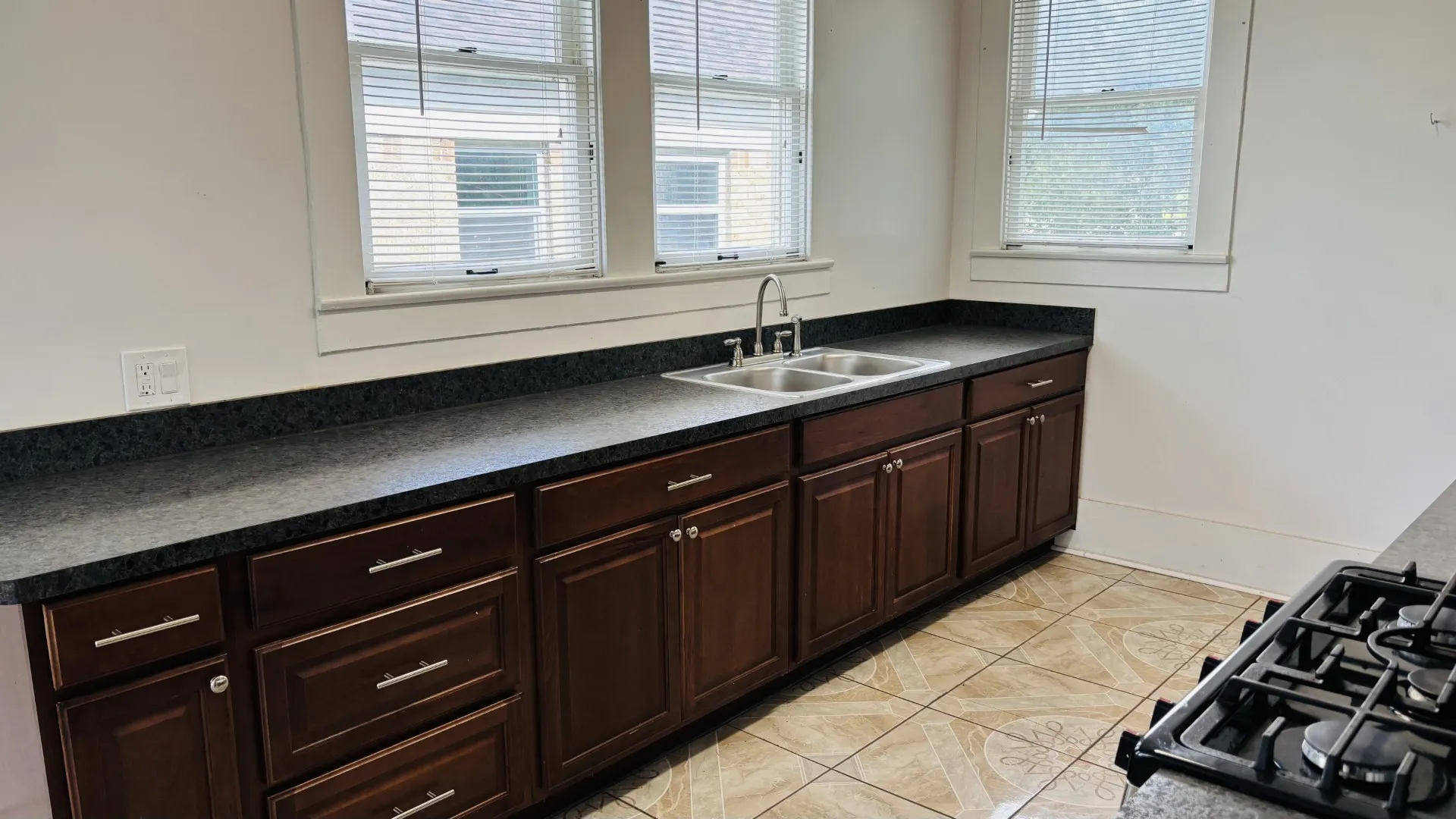 Kitchen featuring dark countertops, light tile patterned floors, dark brown cabinetry, and black gas cooktop