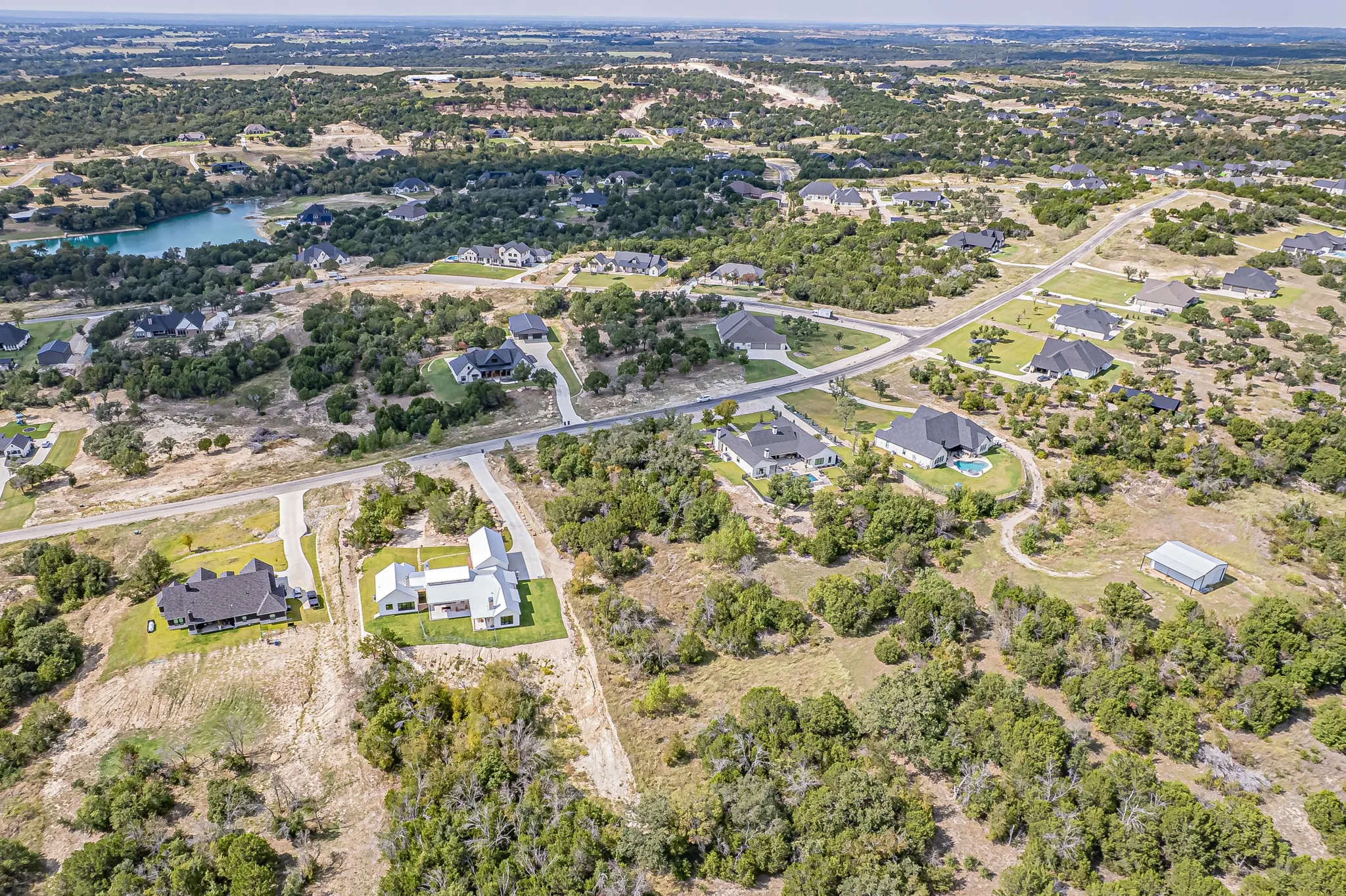 Aerial view of property and surrounding area featuring nearby suburban area and a large body of water